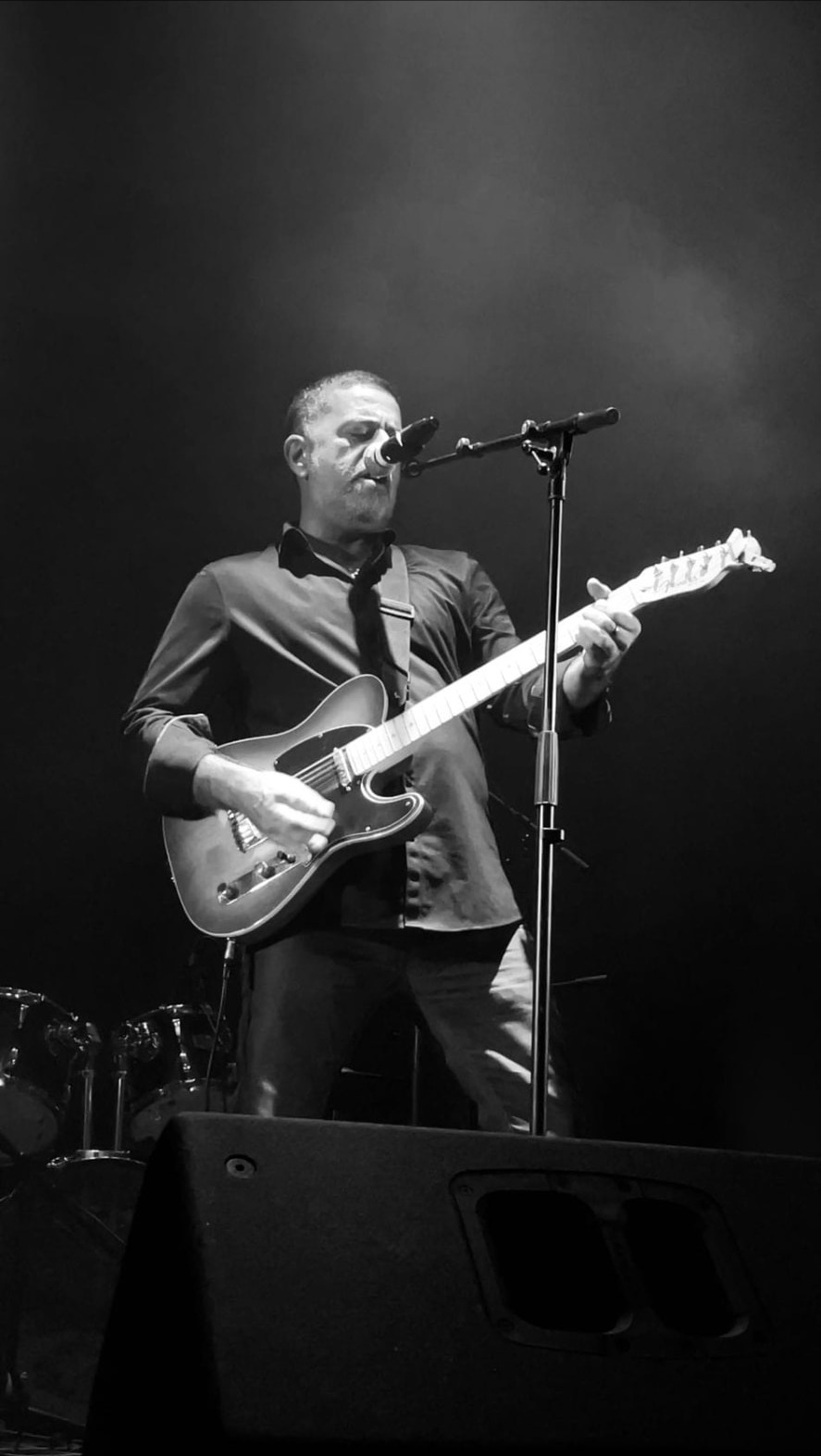 Chanteur guitariste seul en scène, noir et blanc